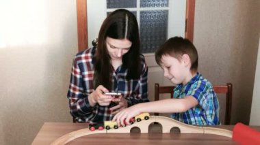 Birlikte oynayan. Anne telefon görünüyor ve son tren, vagonlar ve masada oturan tünel ile ahşap bir demiryolu çalacak.