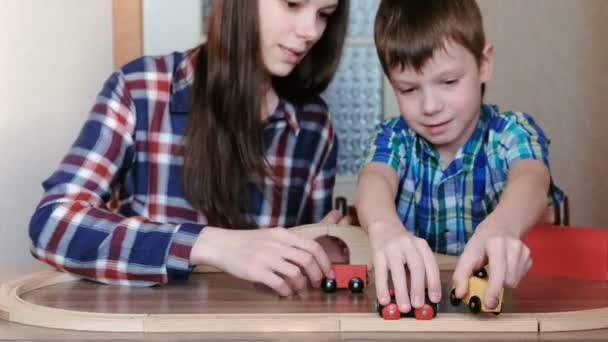 一緒に遊んで。ママと息子は木製の鉄道鉄道、ワゴンやテーブルに座ってトンネルを遊んでいます。. — ストック動画