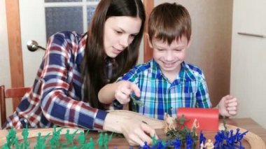 Birlikte oynayan. Anne ve oğlu ahşap bir demiryolu tren, vagonlar ve tünel ile masada oturan plastik askerler ile oynuyorlar.