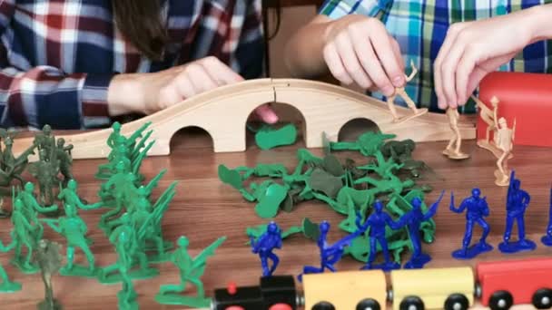 Samenspelen. Closeup moeder en zoons handen spelen een plastic soldaten op tafel — Stockvideo