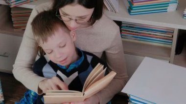 Anne oğlu okumayı öğretir. Aile birlikte bir kitap okuma.