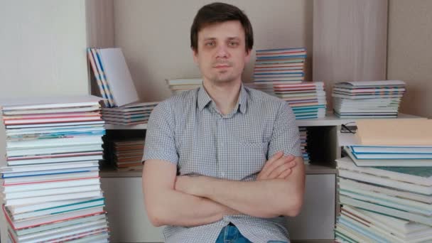 Young brunet man sitting among the books and look at camera. — Stock Video
