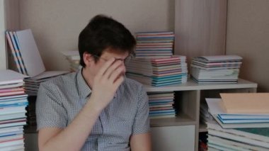 Brunet delikanlı ve onun gözlük koyar bir kitap kitaplar arasında oturan okur.