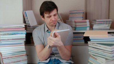 Brunet delikanlı kitapları arasında katta oturan notlar yazıyor.