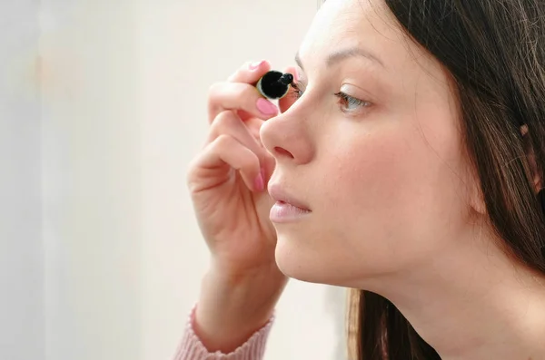 Joven hermosa mujer pinta sus ojos con rímel. Vista lateral . —  Fotos de Stock