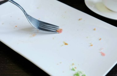 Kadının yakın çekim toplar bir beyaz dikdörtgen plaka yiyecek kalıntıları bir çatal ile el.