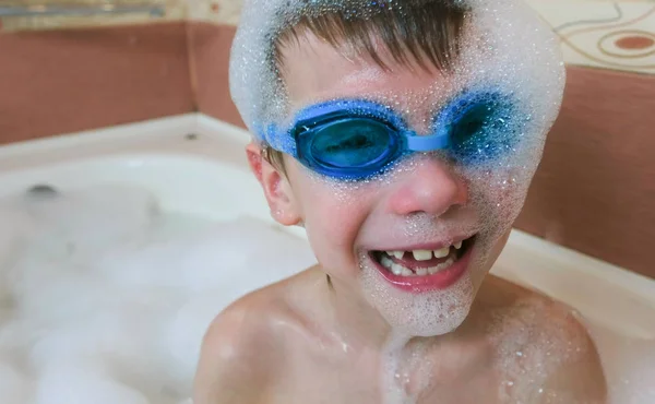 Boy 6-7 years in the foam and goggles for swimming sitting in the bathroom and smiling. Face close-up. — Stock Photo, Image