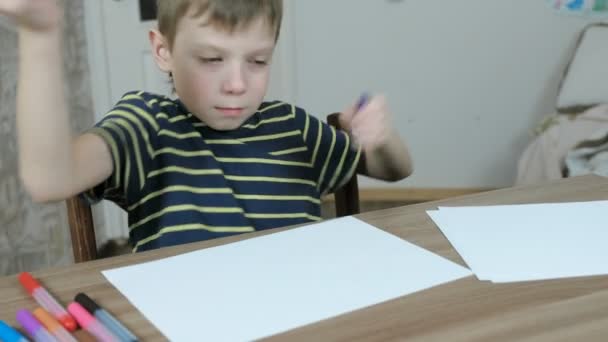 Boy abre o marcador sentado na mesa em seu quarto e reflete sobre o que desenhar . — Vídeo de Stock