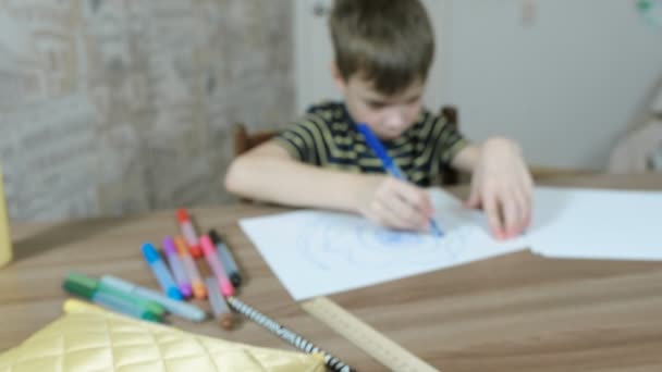 Niño dibujar óvalos con un marcador azul sobre papel blanco. Desenfoque . — Vídeo de stock