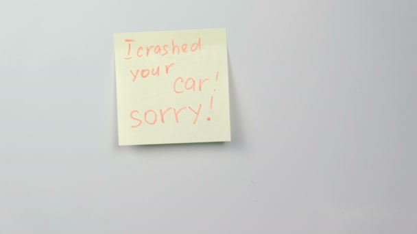 Hoja de papel adhesivo amarillo de primer plano con palabras me estrellé su coche, lo siento en el refrigerador . — Vídeos de Stock