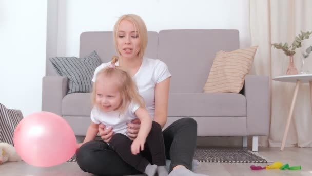 Attractive young blond mom and her charming daughter playing together with pink balloon. — Stock Video