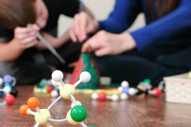 Arka plan bulanıklık. Anne ve oğlu volkan deney yapıyoruz. Volkana su dökmek.