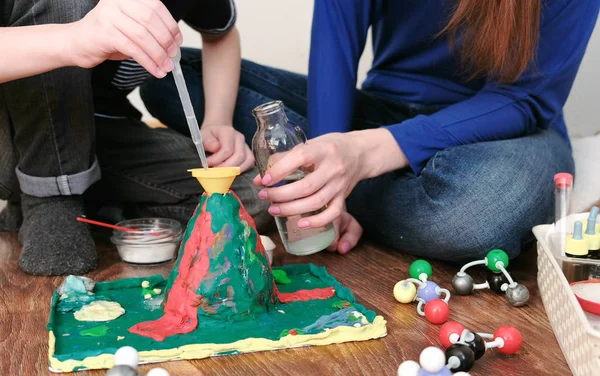 Kimyasal deney. Çocuklar el Close-Up su şişe bir pipet kullanarak volkan huni dökülür..