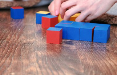 Bir tane renkli mavi şekil küpleri oluşturma anne ve oğulları eller.