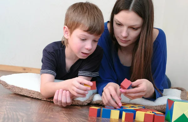 Anya és fia játszik együtt fából készült színes oktatási játék blokkok feküdt a padlón. — Stock Fotó