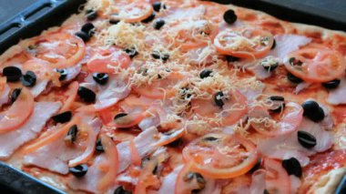 Pizza Hazırlama Cook. Kadının eller rendelenmiş peynir sosu, zeytin, domates ve pastırma ile hamur koymak.