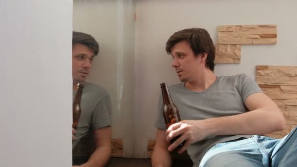 Mannelijke Bachelor in bier en clink drinkfles met zijn spiegelbeeld in de spiegel. — Stockvideo