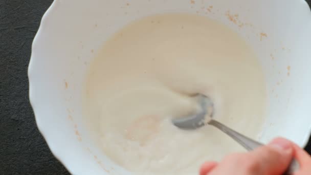 Die Hefe mit der Milch mit einem Esslöffel verrühren. Hefe löst sich in Milch auf. Zubereitung von Hefeteig. — Stockvideo