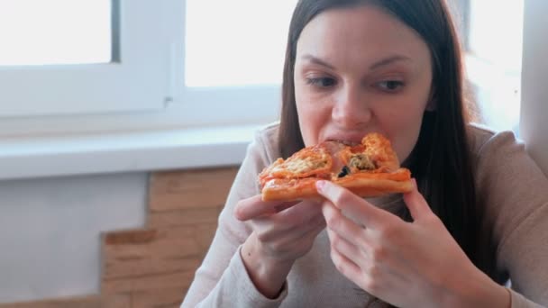 Jonge vrouw is een plak van eigengemaakte pizza eten. — Stockvideo