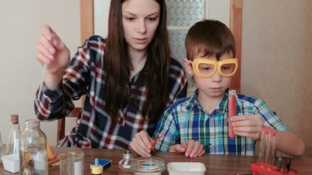 Chemie-Experimente zu Hause. Mutter und Sohn machen eine chemische Reaktion mit der Freisetzung von Gas im Reagenzglas. — Stockvideo