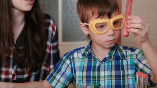 Experimentos de química en casa. Mamá e hijo hacen una reacción química con la liberación de gas en el tubo de ensayo . — Vídeos de Stock