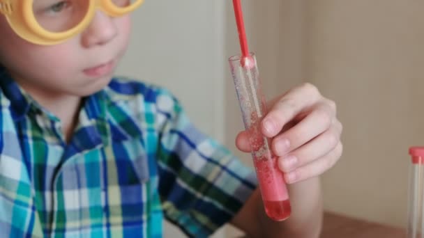 Experimentos de química en casa. Reacción química con la liberación de gas en el tubo de ensayo en las manos del niño . — Vídeo de stock