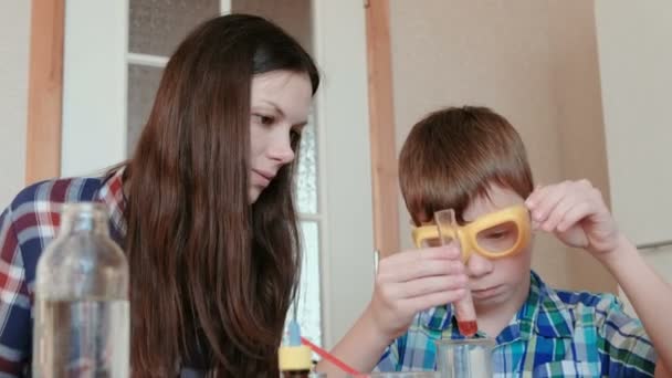 Experimentos de química en casa. Mamá e hijo hacen una reacción química con la liberación de gas en el tubo de ensayo . — Vídeos de Stock