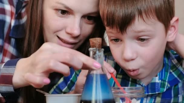 Expériences de chimie à la maison. Maman et son fils font une réaction chimique avec le rejet de gaz dans la fiole . — Video