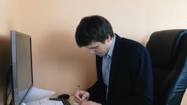 Bilgisayarda çalışan adam. Yazdığı bir şey etiket, kağıt ve ekranda sopa.