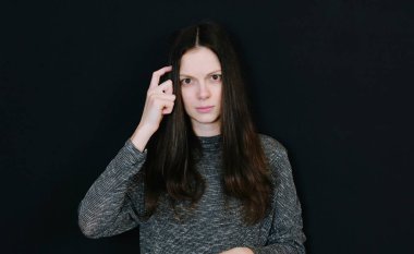 Seni aptal - genç kadın siyah arka planda tapınakta parmağını döner misin.