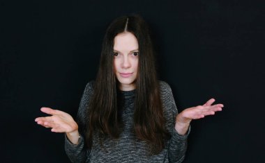 Siyah arka plan onun omuzlarında shrugging genç çekici kadın.