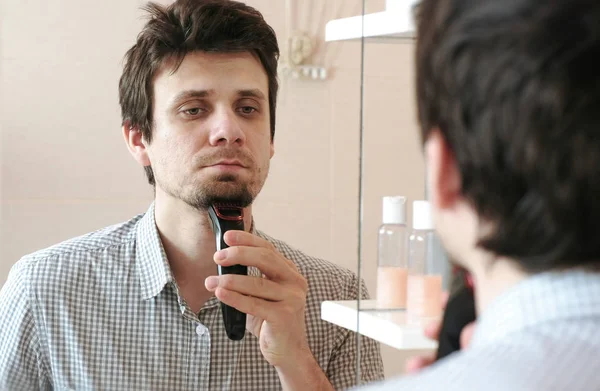 Máquina afeitarse el pelo facial. Joven hombre guapo afeitado en seco con trimmer eléctrico — Foto de Stock