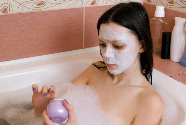Hermosa mujer poniendo una máscara de barro. Aplícale la máscara en la cara. Baño en casa. Spa en casa . — Foto de Stock