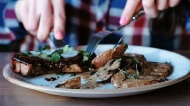 Patates, et suyu ve Yeşiller plaka ve yeme ile kömürlerin üzerinde pişmiş domuz parçası kesme portre kadının el.