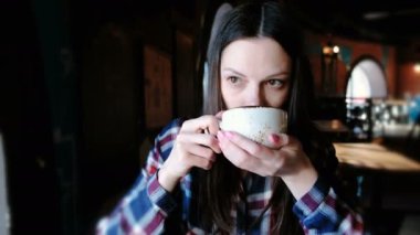 Esmer kadın büyük bir bardaktan çay içme Kareli gömlekli. Yorgun bir çay var.