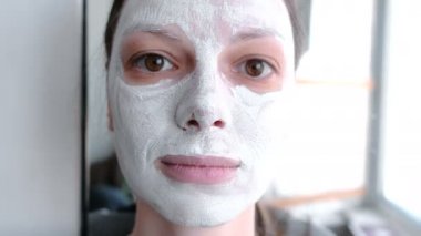  maske bir kadının yüzünde yatıyordu. Kameraya bakarak yakın çekim yüz bağırır ve korkutuyor.