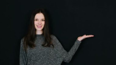 Esmer kadın gülümseyerek el palm sağ siyah arka planda gösterir. Metin için yer.