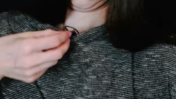 Mãos de mulher de close-up anexa o microfone lavalier à blusa em um fundo preto . — Vídeo de Stock