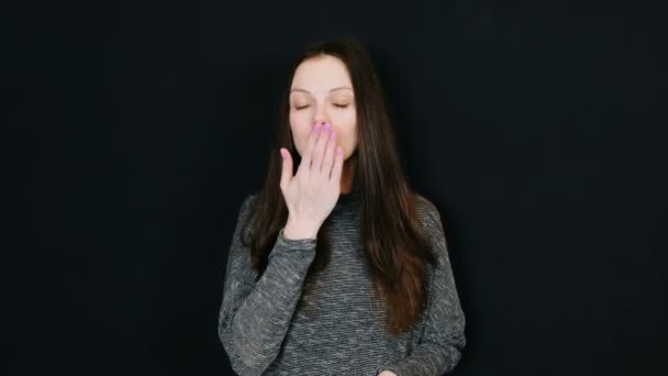 Ung vacker brunett kvinna skickar en air kyss till kameran och leende på svart bakgrund. Utrymme för text. — Stockvideo
