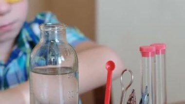 Evde kimya üzerinde deneyler. Tatlı çocuklar el su şişe bir pipet ile tüp içine dökülen. Önden Görünüm.