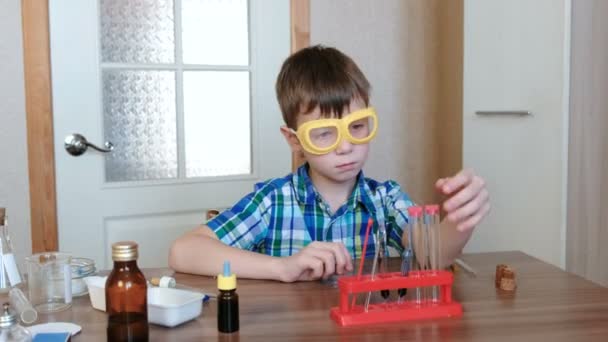 Експерименти з хімії вдома. Хлопчик дивиться на трубку, щоб переконатися, що вона чиста . — стокове відео
