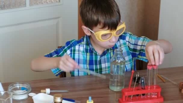 Esperimenti di chimica a casa. Boy prende una bottiglia d'acqua e versa acqua nel tubo con una pipetta. Vista laterale . — Video Stock