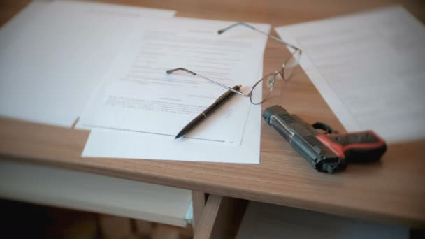 在桌子上的遗嘱, 钢笔, 眼镜和枪. — 图库视频影像