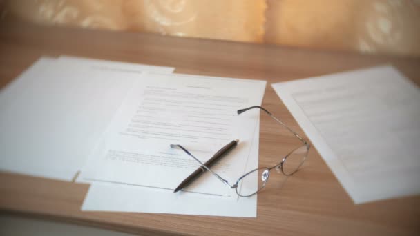 Óculos, documentos e caneta em cima da mesa . — Vídeo de Stock