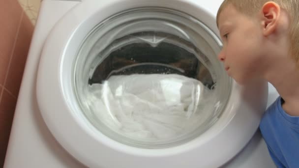 Jongen horloges zoals het bedlinnen wordt gewassen in de wasmachine mashine. — Stockvideo