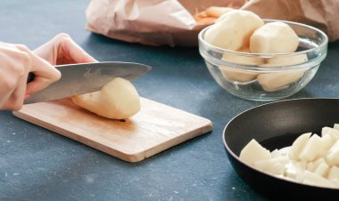 Kapalı kadınların elleri tahta üzerinde patates kesiyor..