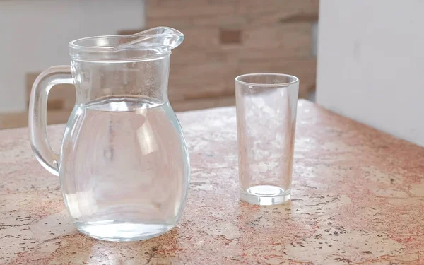 Decantador con agua y un vaso vacío sobre la mesa . —  Fotos de Stock