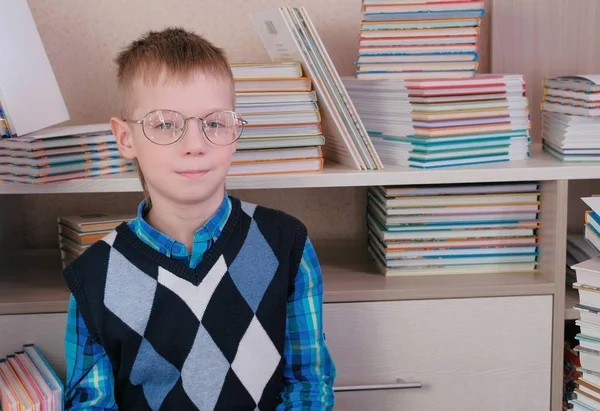 Niño cansado de siete años con gafas sentado en el suelo entre los libros . — Foto de Stock