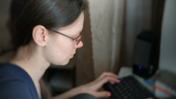 Gözlüklü kadın esmer bir şey bilgisayarda çalışarak klavye üzerinde yazıyor. Yan görünüm. — Stok video