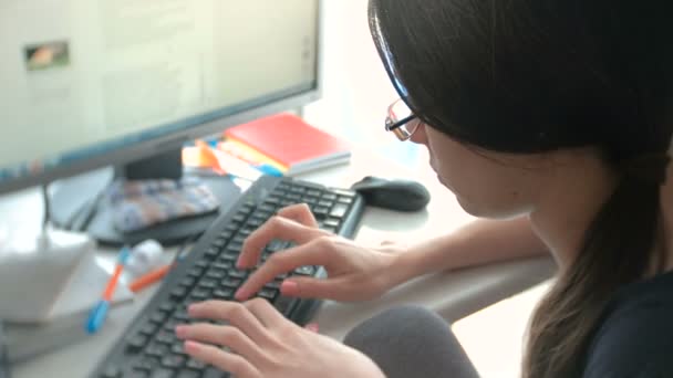 Frau Brünette mit Brille tippt etwas auf der Tastatur, die am Computer arbeitet. Ansicht von oben. — Stockvideo
